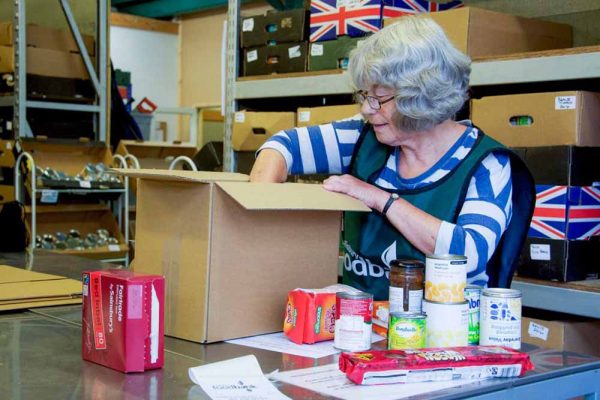 Lady volunteer packing a food box at the Trussell Trust supported by the Ellis Campbell Foundation